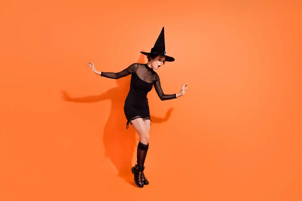 フルサイズの写真の素敵な女性BendオーバーPeek好奇心空のスペース服トレンディーな黒ハロウィン服孤立したオレンジ色の背景 — ストック写真