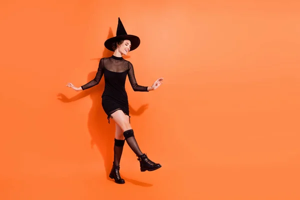 フル長さ写真のWinsome若い女性Disthequeクラブウェアスタイリッシュな黒ハロウィン魔女の外観隔離されたオレンジ色の背景 — ストック写真