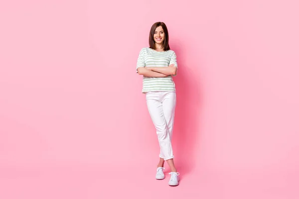 フルサイズ写真の素敵な素敵な楽観的な女の子服ストライプTシャツ白いパンツスニーカー腕交差孤立上ピンク色背景 — ストック写真