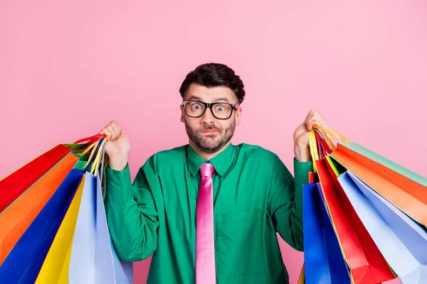 Photo of funny unsure guy wear green shirt spectacles rising bargains shrugging shoulders isolated pink color background.