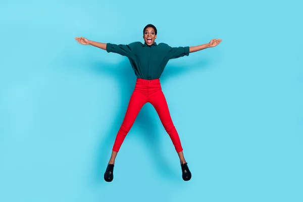 Photo of sweet impressed androgynous human wear green shirt jumping high like star isolated blue color background.