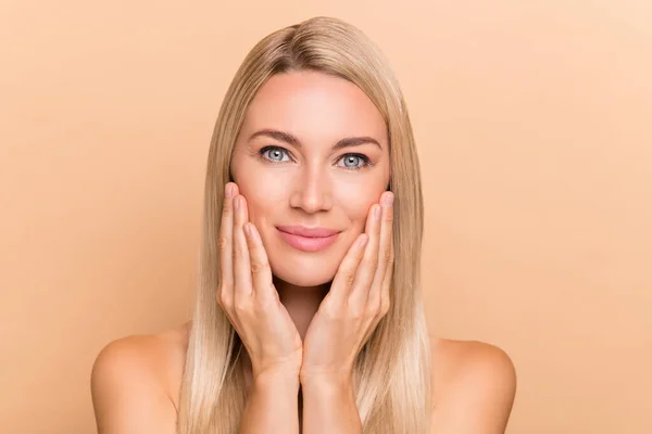 Photo of joyful lady touch hands cheeks enjoy aesthetic silky skin after cream lotion wash isolated over beige color background.