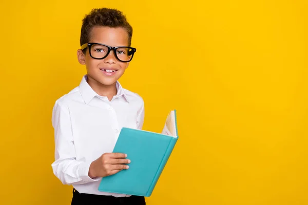 賢いかわいい男の子の学習者の写真眼鏡をかけますホールドコピー本の読み取りタスクの質問演習空のスペース黄色の色の背景に隔離 — ストック写真