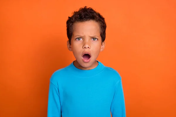 驚くべき心配の少年の写真青いトレンディーなセーターを着てオレンジの背景に隔離された否定的なニュースに感銘を受けた — ストック写真