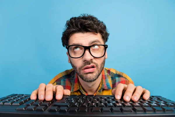 Photo of thinking brunet guy type keyboard look up wear eyewear checkered shirt isolated on blue color background.