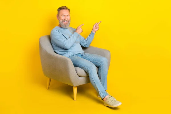 正の高齢者の完全なサイズの肖像椅子に座る指空のスペースを示す黄色の色の背景に隔離 — ストック写真