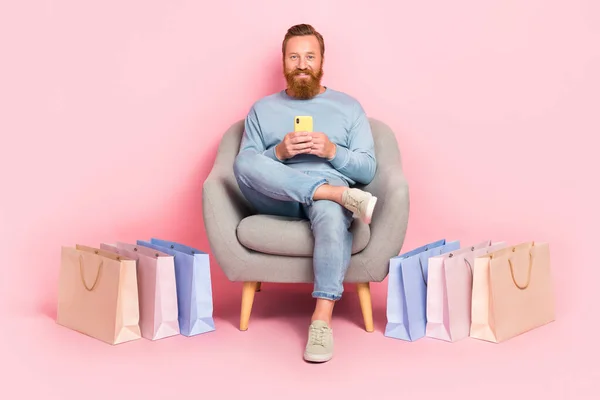 フルサイズの写真の正男座る椅子ホールド使用電話Eshopping絶縁上ピンク色背景 — ストック写真