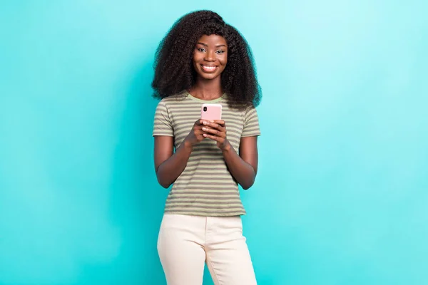 かわいい女性の写真は 現代的なデバイスを通信縞模様のTシャツを身に着けている孤立ターコイズ色の背景 — ストック写真