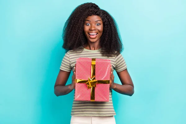 Photo of cute impressed girl dressed green t-shirt smiling getting present box isolated teal color background.