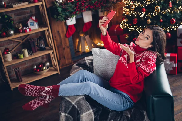 Full size portrait of lovely pretty person sit chair hold telephone make selfie arm send air kiss wear x-mas pullover indoors.