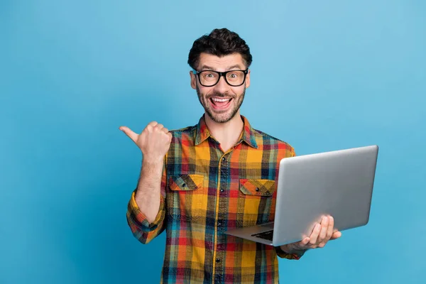 时髦的黑发男人拿着手提电脑指纹识别器的照片 穿着格子花衬衫 蓝色背景隔离 — 图库照片