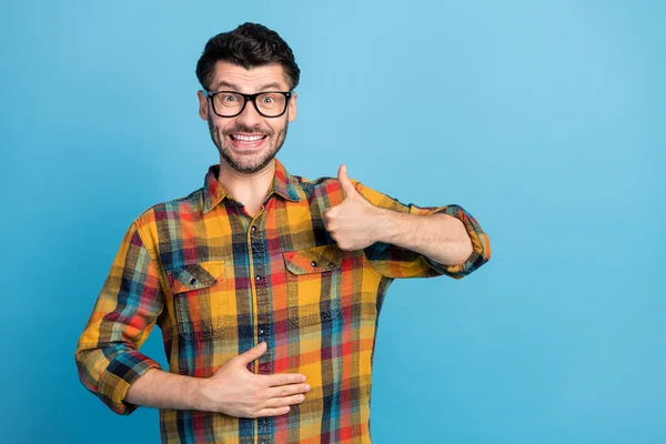 穿着格子衬衫 喜形于色的戴眼镜的快乐而积极的男人的照片 看上去像一只被蓝色背景隔离的手臂在胃部 — 图库照片