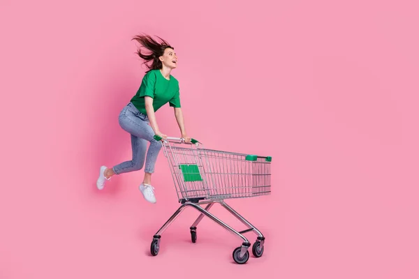 全长照片 喜形于色的女子跳跃冲刺冲刺超级市场推车被粉色背景隔离 — 图库照片