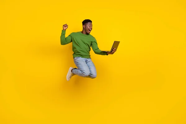フル長いですボディサイズビューのハンサムなトレンディーな男ジャンプ使用してノートパソコン喜び絶縁上鮮やかな黄色の背景 — ストック写真