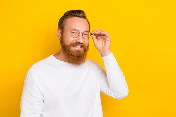 Portrait of positive friendly person hand touch glasses toothy smile isolated on yellow color background.