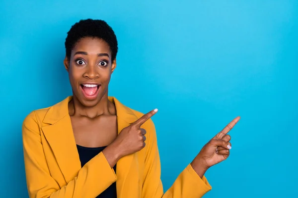 Photo of excited shocked person direct fingers empty space open mouth isolated on blue color background.