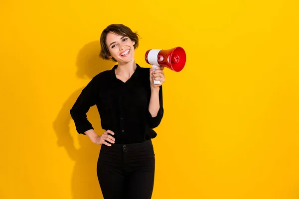 Photo of excited dreamy lady wear black shirt holding megaphone empty space isolated yellow color background.