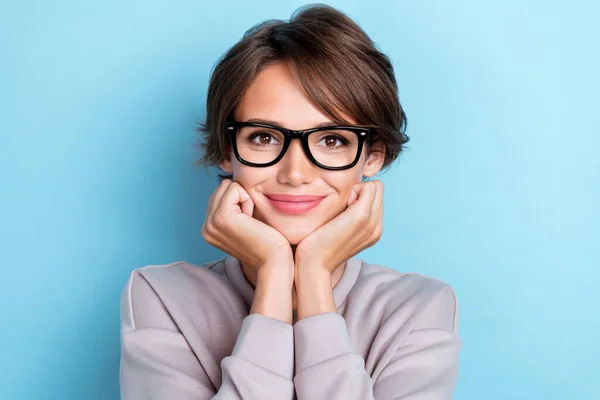 Photo of sweet cute nice gentle lady arm under chin touch cheekbones wear stylish eyeglasses clothes isolated on blue color background.