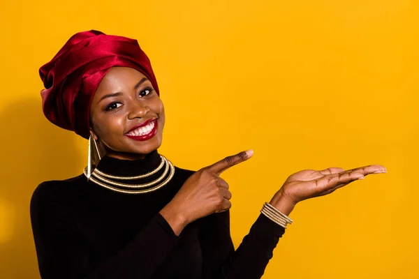 Photo of cheerful friendly lady direct finger hand palm hold empty space isolated on yellow color background.