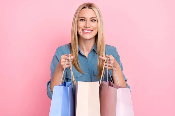 満足の肖像画かなり素敵な女性の服ブルーシャツホールドショッピングバッグショーあなたに孤立した新しい服ピンク色の背景 — ストック写真