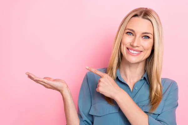 Closeup photo of young positive business lady wear blue formal blouse hold palm finger pointing empty space profit product isolated on pink color background.