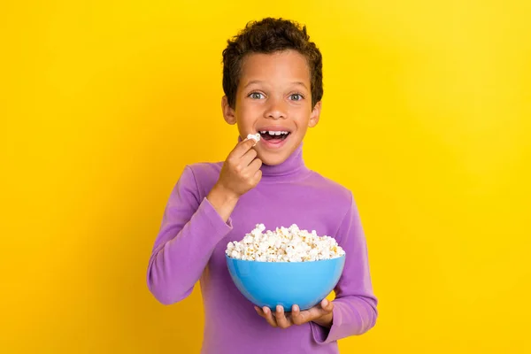 Photo of excited funky person arms hold eat popcorn plate have good mood isolated on yellow color background.