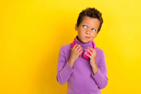 Photo of minded boy look interested empty space hesitate brainstorming isolated on yellow color background.