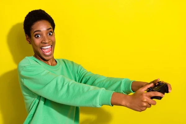 Photo of funny excited trans person wear green sweater enjoying playstation isolated yellow color background.