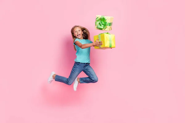 フル長さ写真のかなり興奮小さな子供服の革のTシャツジャンプ高投げギフト隔離されたピンク色の背景 — ストック写真
