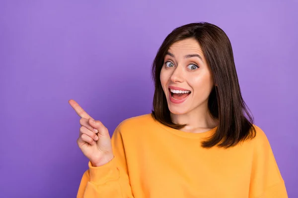 Closeup photo of young woman bob brown hair excited toothy finger point empty space demonstrate ad offer isolated on purple color background.