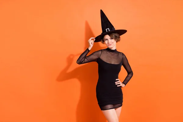 ファンキーな女性の写真は黒の魔女のドレスの手キャップ笑顔空のスペース孤立オレンジ色の背景 — ストック写真