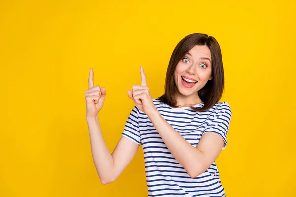 Photo of young attractive pretty funny woman finger directing empty space good new retail price reaction isolated on yellow color background.