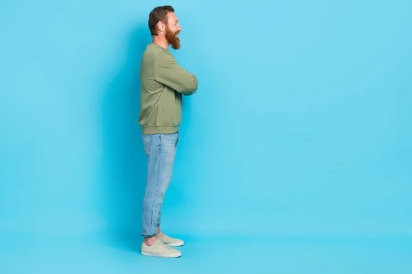 Full body profile photo of handsome young man folded arms empty space dressed stylish khaki outfit isolated on aquamarine color background.