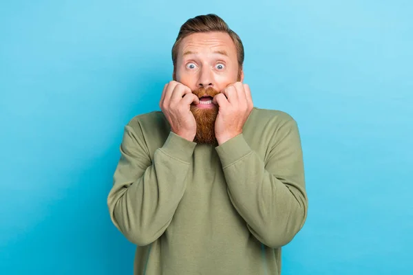 Portrait of frightened unhappy guy with red hair wear khaki pullover fingers on mouth cheekbones isolated on turquoise color background.