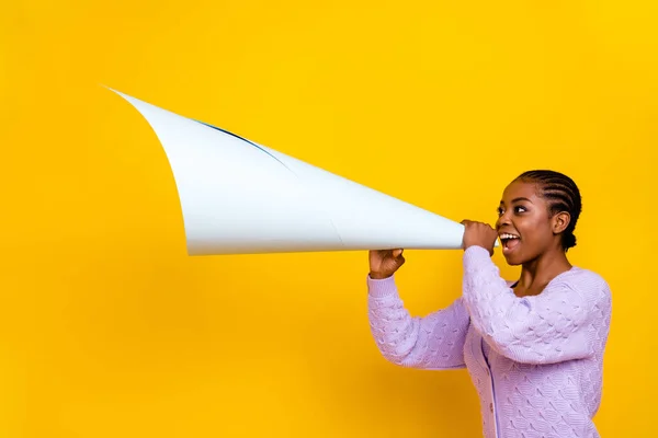 Profile portrait of excited funny lady hands hold paper speaker say tell empty space isolated on yellow color background.