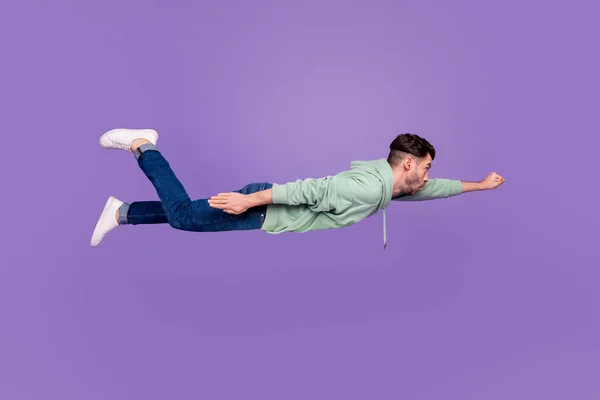 魅力的な若い男の全身写真飛行スーパーマン拳自信を持って身に着けているスタイリッシュなカーキ服紫色の背景に隔離 — ストック写真