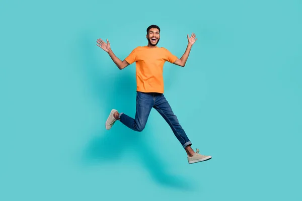 面白いです興奮男の完全な長さの写真を着てオレンジTシャツジャンプ高い笑顔孤立したティール色の背景 — ストック写真