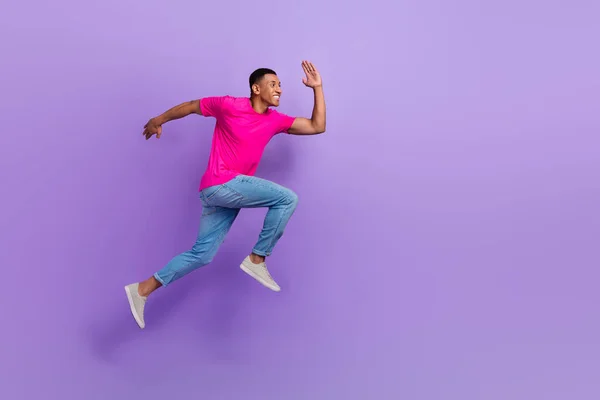 フルボディプロフィール写真の活動的なスポーティーな男ジャンプ実行急いで空のスペース孤立した上の紫の色の背景 — ストック写真