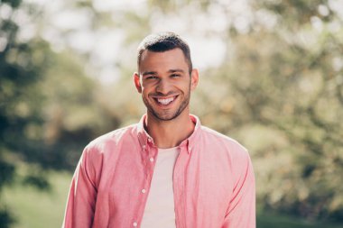 Photo of handsome attractive young guy dressed pink casual shirt smiling enjoying warm weather outdoors backyard. clipart