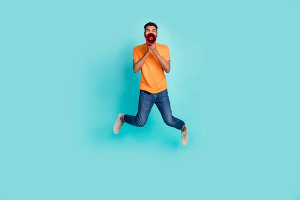 Full body photo of overjoyed person jumping hands hold loudspeaker say isolated on turquoise color background.