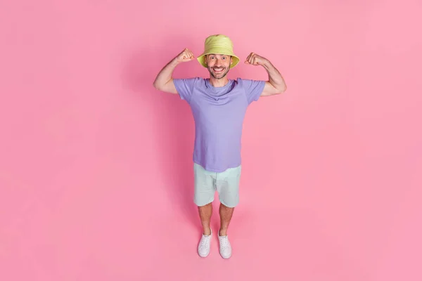 フルサイズ写真高角度ビューのハンサムな若い男の筋肉を示す曲げ摩耗スタイリッシュな青の衣装ピンク色の背景に隔離 — ストック写真