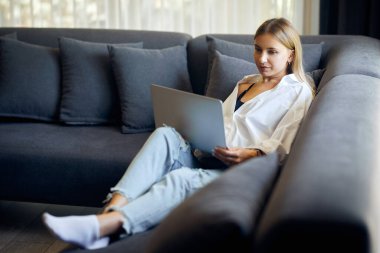 Elinde dizüstü bilgisayarı olan bir kadın arıyor ve gülümsüyor. Arka plandaki merdivenler.