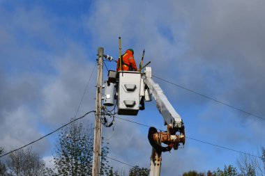 Power Lines Servicemen working on hydroelectricity lines and hydro transformer from a lift truck clipart