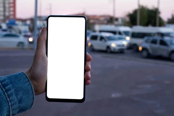 女性使用黑色智能手机 模仿女性手持空白白色桌面屏幕手机的形象 后面是一片混乱的城市景观 — 图库照片