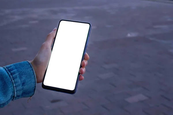 ブラックスマートフォンを使う女性 歩道を歩きながら白いデスクトップ画面と携帯電話を保持している女性の手のモックアップイメージ — ストック写真