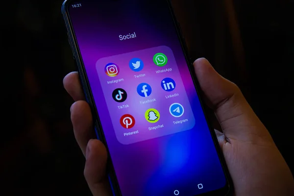 Afyonkarahisar, Türkiye - 10 Aralık 2021: Sosyal medya uygulamaları (Instagram, Twitter, Whatsapp, TikTok, Facebook, LinkedIn, Pinterest, Snapchat, Telegram) ekranda, ellerinde akıllı telefon bulunan simgeler.