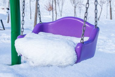 Karla kaplı plastik salıncak. Kışın parkta sallanmak. Kış arkaplan fotoğrafı.