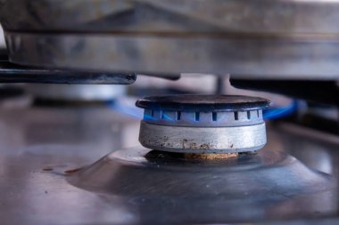 Yakın çekim mutfak gaz ocağı mavi alevle yanıyor.