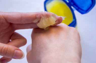 Woman using petroleum jelly for skin care. Young girl applying moisturizing cream on her hand. clipart