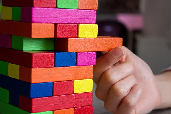Evde ahşap kule oyunu oynuyoruz. Masanın üzerinde renkli tahta bloklar var..